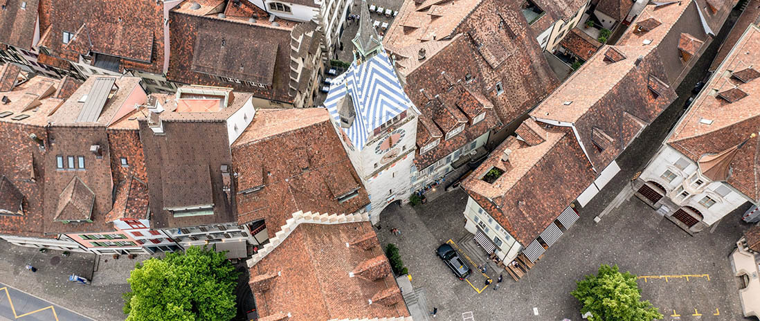 Luftaufnahme der Zuger Altstadt mit Blick auf den Zytturm und die markanten Ziegeldächer historischer Gebäude in der Nähe des Neubauprojekts Colin.