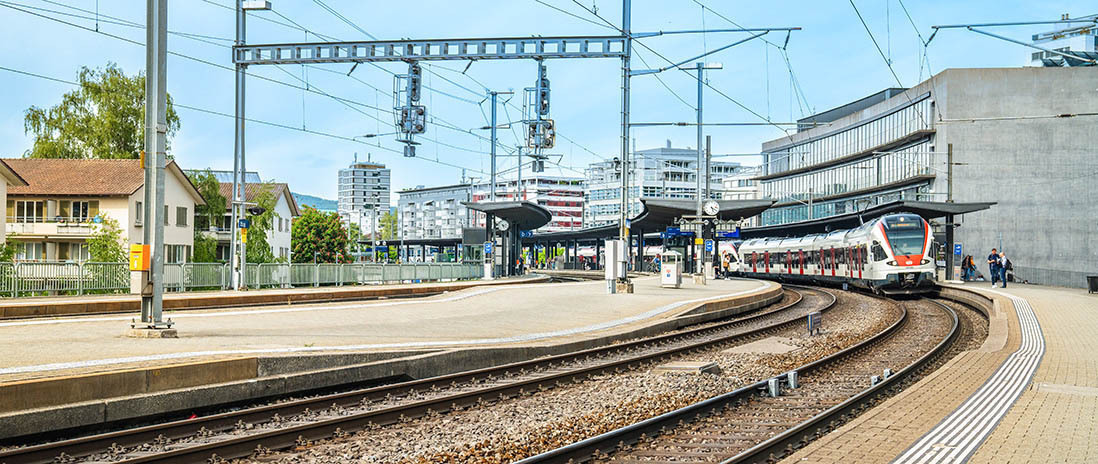 Der Bahnhof Zug mit einfahrendem SBB-Zug – moderner Knotenpunkt mit guter Anbindung in der Nähe des Neubauprojekts Colin.
