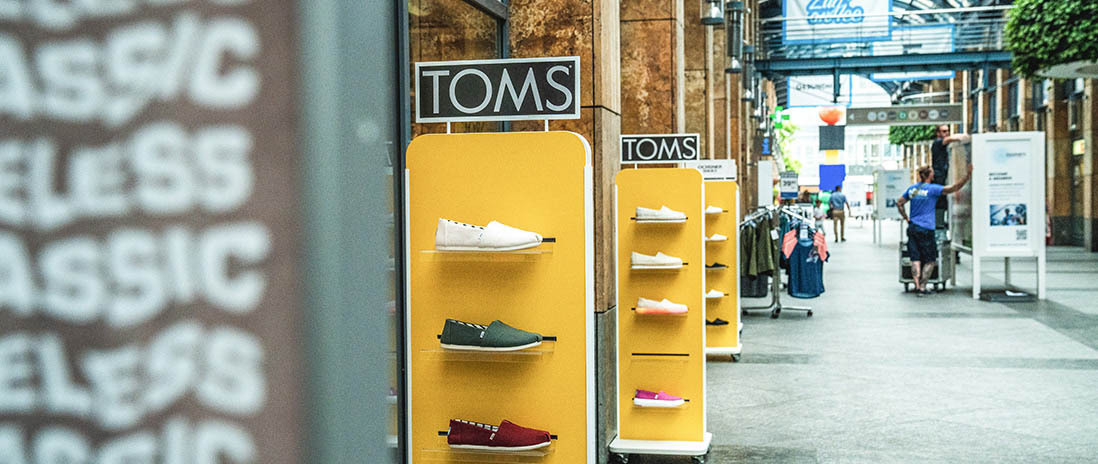 Innenansicht eines Einkaufszentrums in Zug mit TOMS-Schuh-Display im Vordergrund in der Nähe des Neubauprojekts Colin.