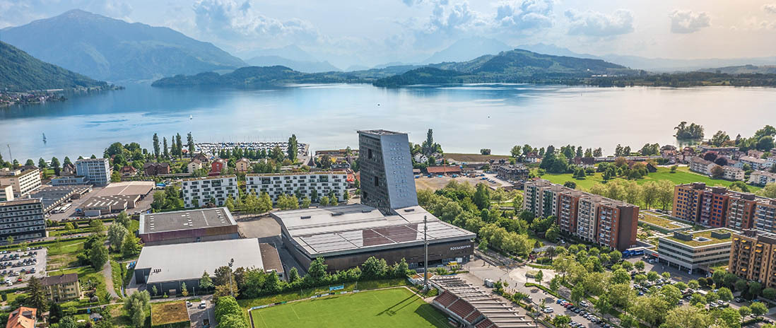 uftaufnahme von Zug-Mitte mit Sportarena, Hochhaus und Blick auf den Zugersee in der Nähe des Neubauprojekts Colin.